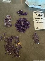 Overview of several piles of loose amethyst stones on tabletop
