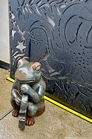 frog statue beside wall panel showing size reference with tape measure