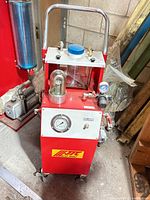 Front view of red JTC pneumatic brake bleeder showing handle, gauge, logo, fluid dome, wheels