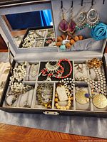 Open Songmics jewelry box showing assorted jewelry pieces in compartments and earrings on hooks
