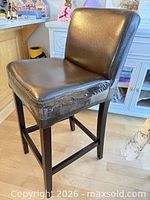 Front-left view of brown faux leather counter-height chair showing seat wear and tape