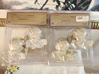 Two sealed packages each containing two ivory cherub finials