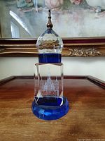 Full view showing base, clear block with etched cathedral, blue dome top, metal finial