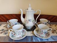 Full set displayed: teapot on underplate surrounded by four cup and saucer pairs