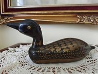 Full side view of duck coin bank on lace doily