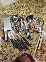 Overview of all utensils, knives, cleavers, flatware and wooden chopsticks on countertop