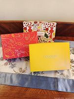 Three L'Occitane gift set boxes: yellow, red and patterned bag