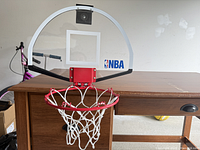 Front view showing clear backboard, red rim, white net, NBA logo