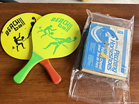 Two yellow Beach Ball paddles beside sealed Royal Pitching Horseshoes box