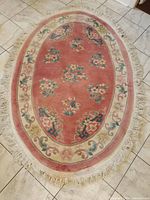 Full view of oval floral rug showing pattern, fringe, and overall wear