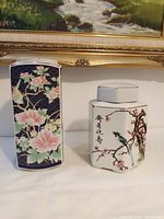 Both porcelain tea canisters with lids side by side