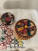 Both wooden trinket boxes with lids closed, showing top decorations