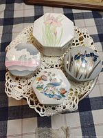 All four porcelain trinket boxes grouped on lace doily