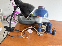 Shark handheld vacuum, black clamp lamp, blue accent lamp, cords, bulbs visible