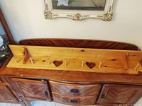 Front view showing entire pine shelf, pegs, heart cutouts, top shelf