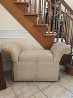 Front view of beige upholstered storage bench with rolled arms and skirted base