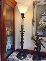 Full view of illuminated barley twist torchiere table lamp beside cabinet