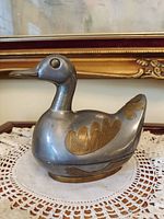 Profile view of silver-tone duck trinket box showing gold-tone feather inlays