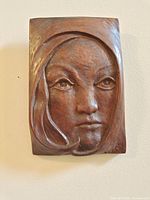 Front view of carved wood plaque showing full female face relief