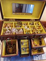 open jewelry box with compartments and drawers displaying costume jewelry
