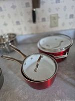 Two red Bialetti saucepans stacked with lids on kitchen counter