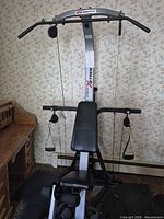 Full view of Bowflex Xtreme home gym showing lat bar, bench, cables and leg developer