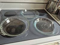 Three clear glass pie plates on stovetop