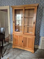 Full view of oak veneer china cabinet hutch showing upper glass doors and lower wood doors