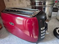 Angled view showing red body, two slots, surrounding kitchen items