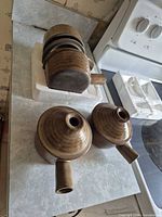 Two stoneware kyusu teapots with side handles shown from top with lids removed, plus unrelated stacked mugs in background
