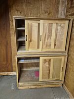Front view of stacked two-piece cabinet showing sliding doors and shelves