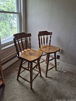 Both wooden bar stools by window