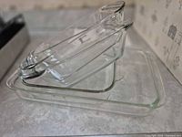 Stacked view of three clear glass bakeware pieces showing relative sizes and shapes