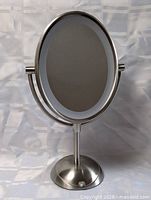 Front view showing oval mirror, light ring and metal frame