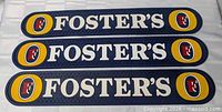 Three Foster's beer bar mats aligned horizontally, showing full top view