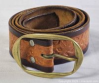 Rolled belt showing buckle, leather tooling and dark brown edges