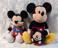 Front view of all three Mickey Mouse plush dolls