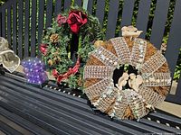 Both wreaths, ornament container and hanger displayed on bench