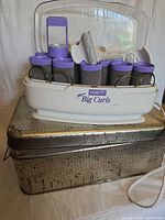 Full hot roller set on metal tin showing base, lid, rollers, clips