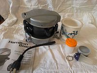 All items together: sandwich maker, power cord, manual, ceramic crock, three plastic containers
