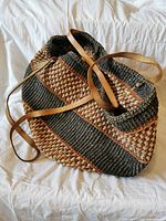 Angled top view of woven tote showing overall shape, pattern and leather straps