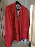 Front view of coral blazer on hanger showing overall style and color