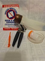 Front view showing cookbook, can opener, batter dispenser, glass dish, peeler, shaker