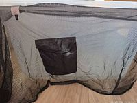 Full view of black mesh cover-up with front nylon pocket displayed
