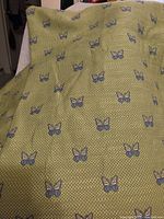 Overall view of olive green fabric with embroidered butterflies