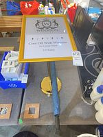 Full view of sign stand showing frame with insert, pole, base, attached blue umbrella