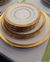 Stacked dinner, salad, and side plates showing gold rim pattern