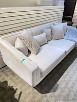 Full view of beige 3-seat sofa with pillows and throw