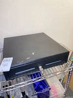 Black metal cash drawer on shelf