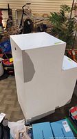 Two white display pedestals among assorted items